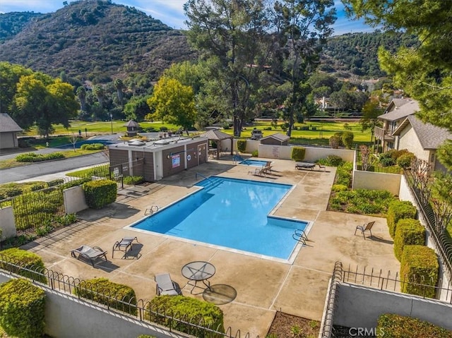 community pool featuring a patio area, fence, and a mountain view