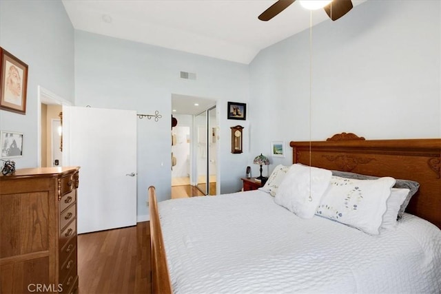 bedroom featuring visible vents, ceiling fan, wood finished floors, ensuite bathroom, and vaulted ceiling