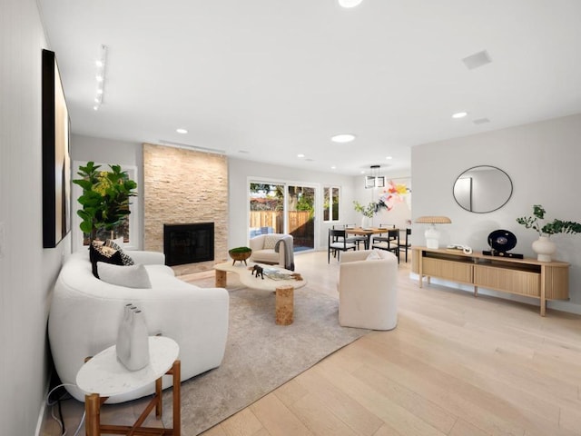 living room with a stone fireplace and light wood-type flooring