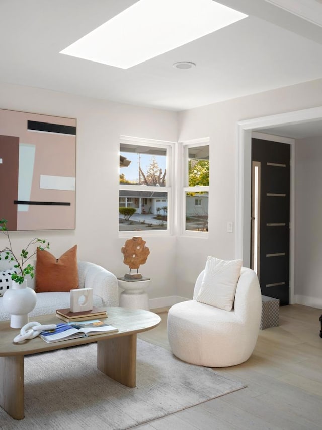 living area with hardwood / wood-style flooring and a skylight