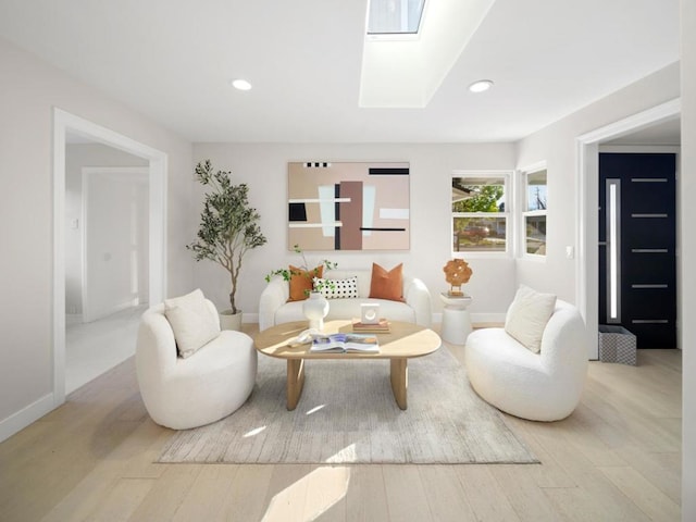 living room featuring light wood-type flooring and a skylight