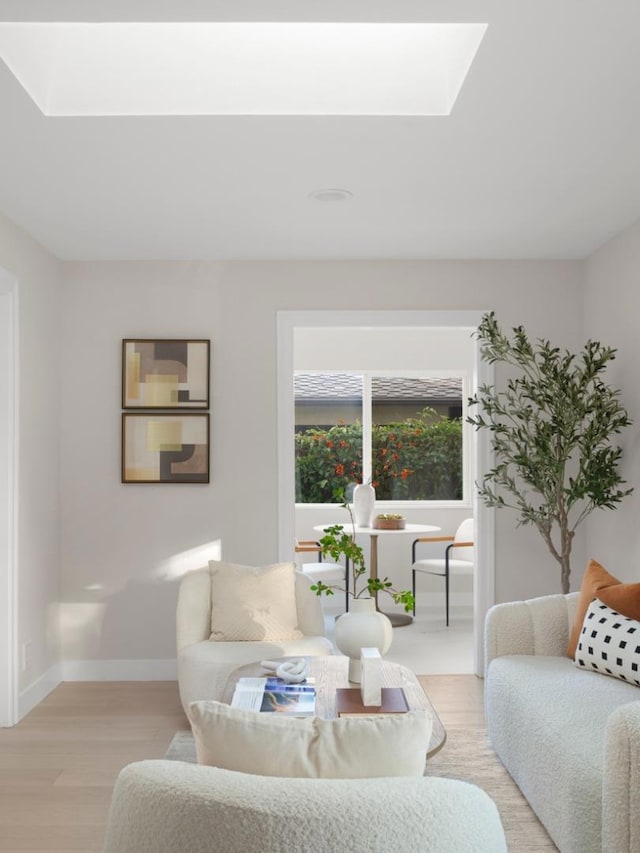 living room with a skylight and light hardwood / wood-style floors