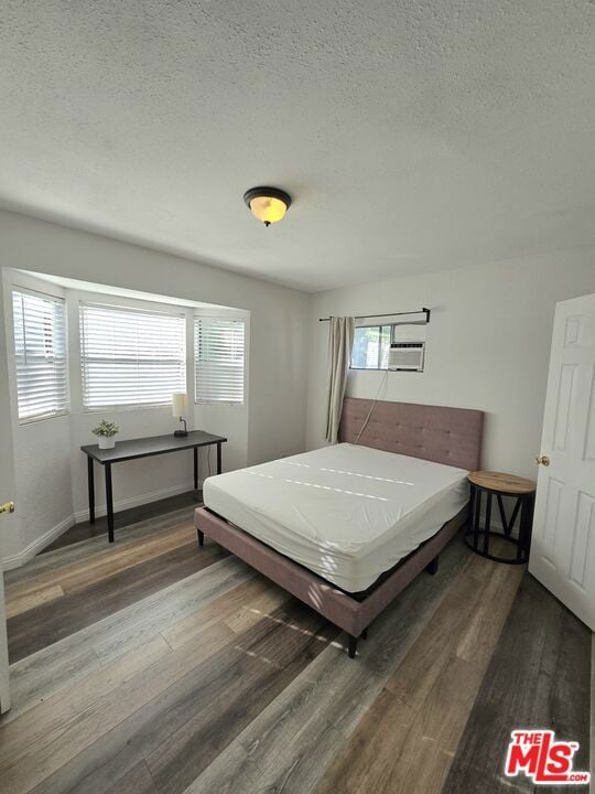 bedroom with dark hardwood / wood-style flooring and a textured ceiling