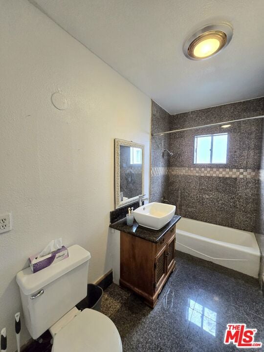 full bathroom featuring tiled shower / bath combo, vanity, and toilet