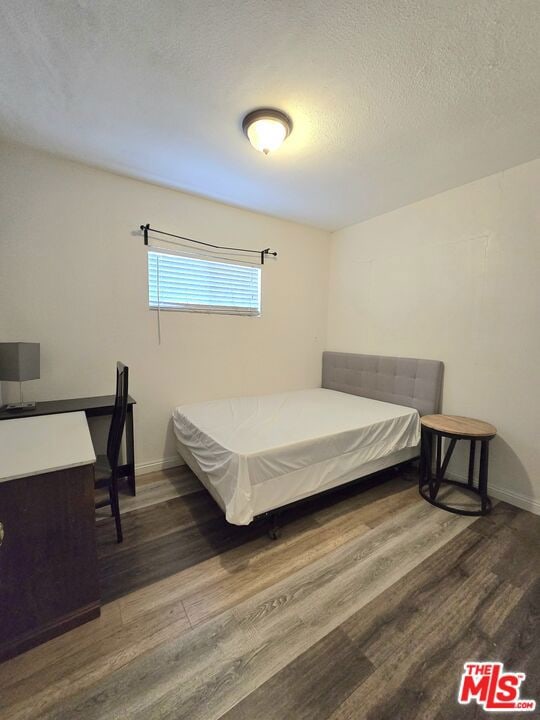 bedroom featuring a textured ceiling and dark hardwood / wood-style flooring