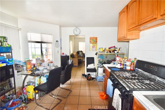 kitchen featuring tile countertops, light tile patterned floors, backsplash, and black appliances