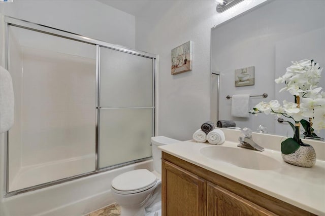 full bathroom featuring vanity, shower / bath combination with glass door, and toilet