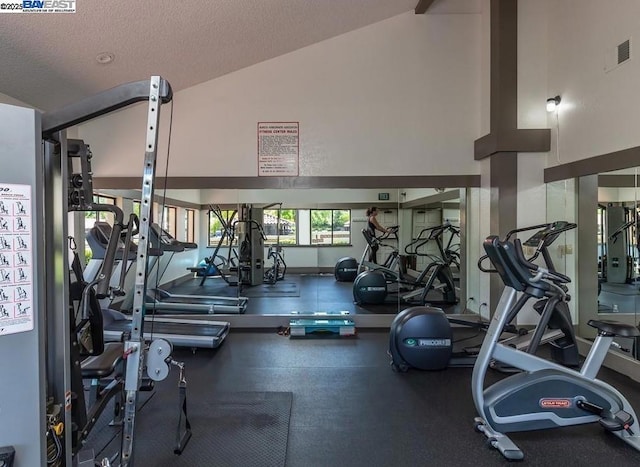 gym with high vaulted ceiling and a textured ceiling