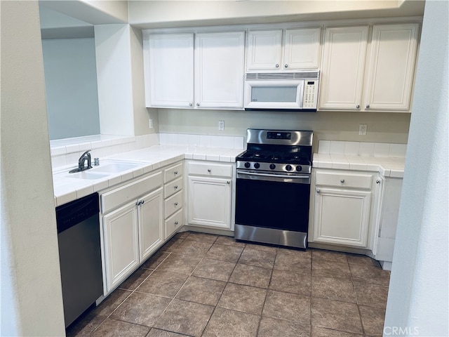 kitchen with white cabinetry, sink, tile countertops, and stainless steel appliances