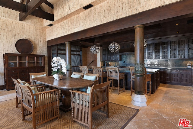 dining area with light tile patterned floors, decorative columns, and a high ceiling