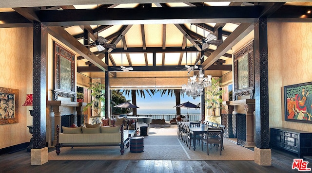 living room featuring a water view, high vaulted ceiling, hardwood / wood-style flooring, beam ceiling, and ceiling fan with notable chandelier