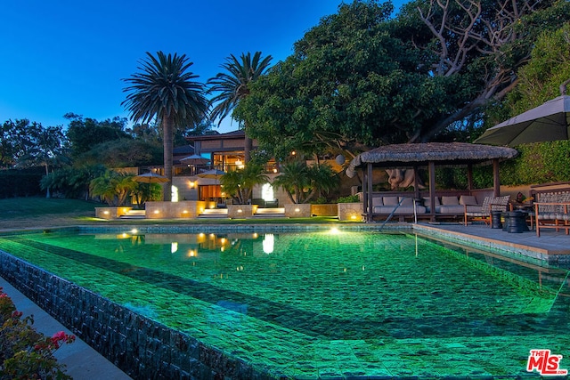 pool at dusk featuring a gazebo and outdoor lounge area