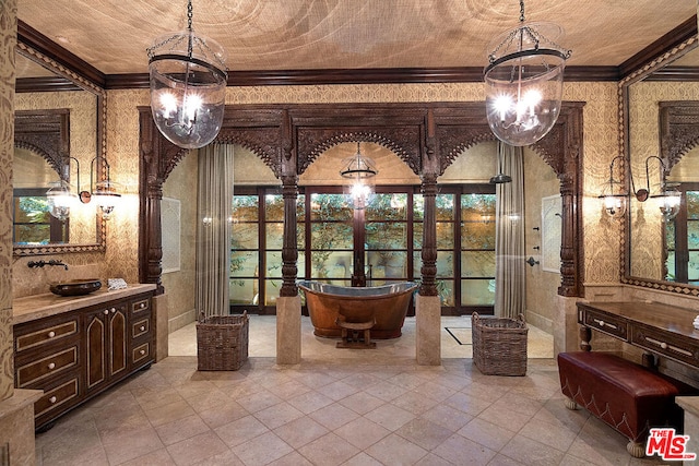 bathroom with crown molding, vanity, a chandelier, and a tub to relax in