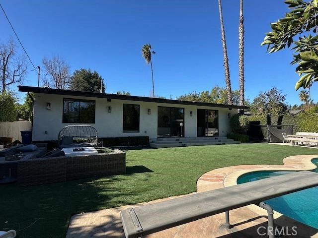 back of property with a fenced in pool, an outdoor hangout area, a patio, and a lawn