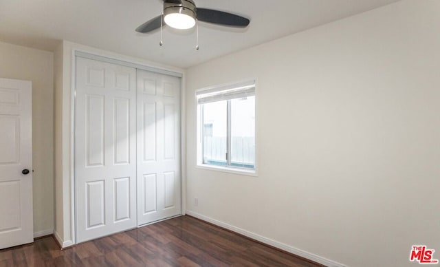 unfurnished bedroom featuring dark wood-type flooring, a closet, and ceiling fan