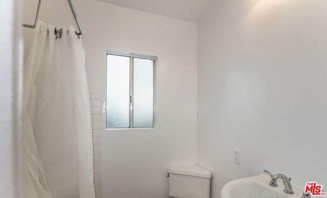 bathroom with sink, curtained shower, and toilet