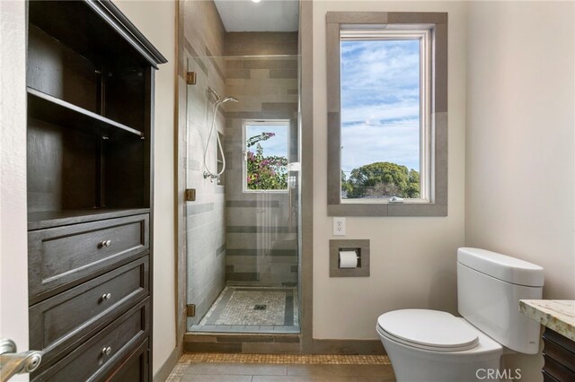 bathroom featuring tile patterned flooring, vanity, toilet, and walk in shower