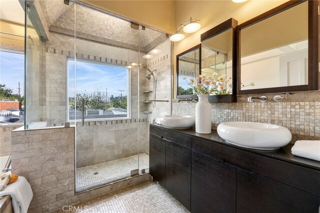 bathroom featuring vanity, backsplash, and tiled shower