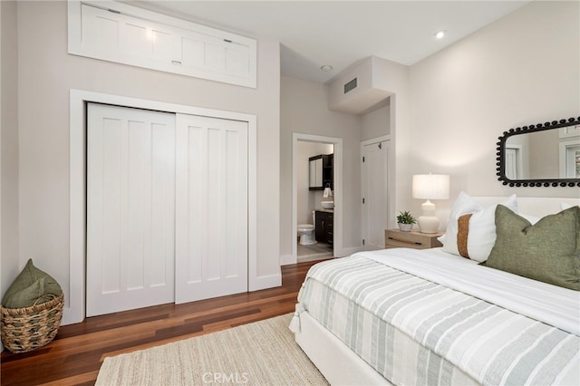 bedroom with dark wood-type flooring, ensuite bath, and a closet