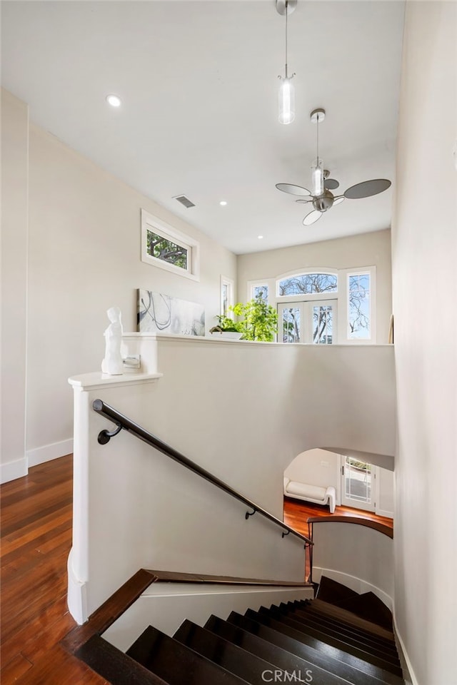 stairs with hardwood / wood-style flooring and ceiling fan