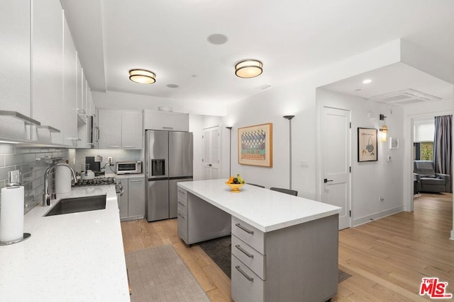 kitchen with sink, hanging light fixtures, a center island, stainless steel refrigerator with ice dispenser, and light hardwood / wood-style flooring