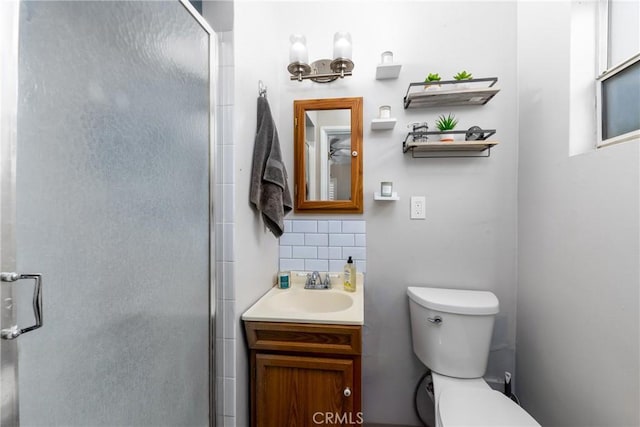 bathroom featuring tasteful backsplash, vanity, a shower with door, and toilet