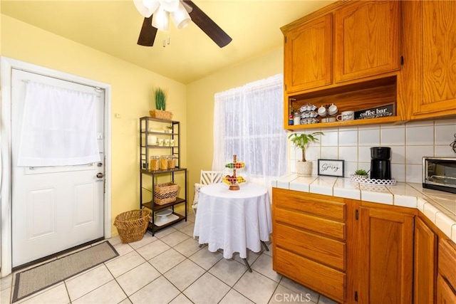 kitchen with ceiling fan, tile countertops, light tile patterned floors, and backsplash