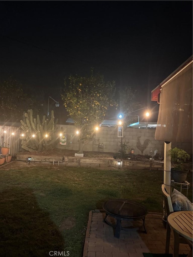 yard at night with a patio area and an outdoor fire pit