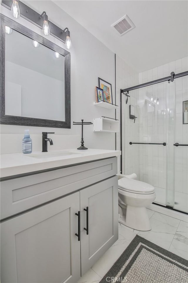 bathroom featuring vanity, a shower with shower door, and toilet