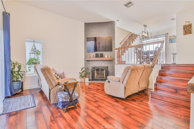 living room with a notable chandelier, hardwood / wood-style flooring, and a fireplace