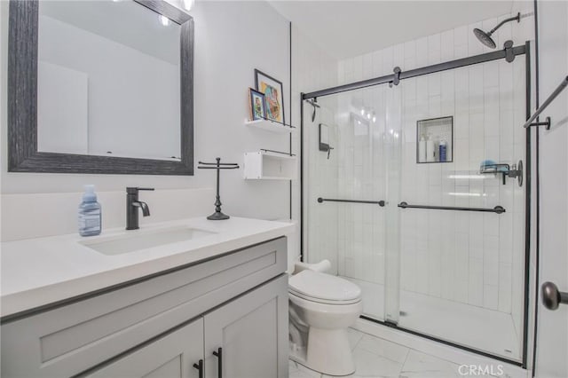 bathroom featuring vanity, a shower with shower door, and toilet