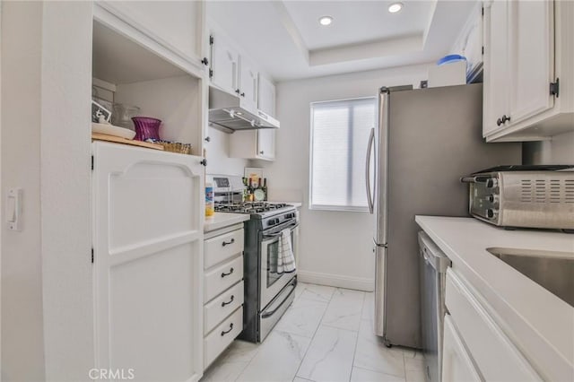 kitchen with appliances with stainless steel finishes, white cabinets, and a tray ceiling