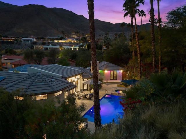 pool at dusk featuring a mountain view and a patio area