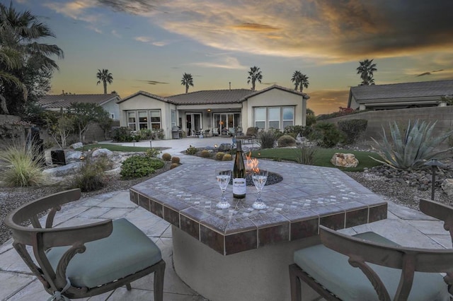 back house at dusk featuring a patio