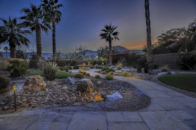 yard at dusk featuring a mountain view and a patio