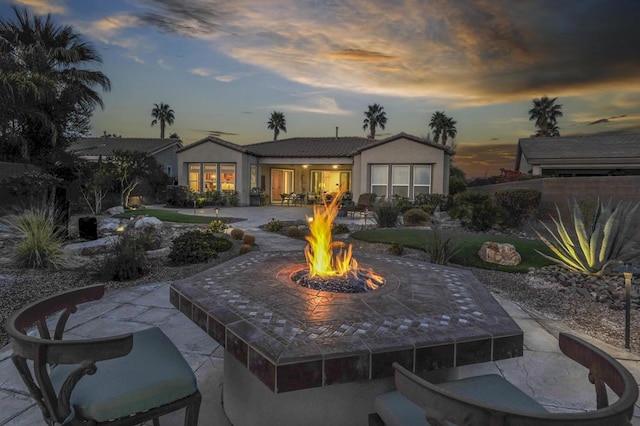 back house at dusk featuring a patio area and an outdoor fire pit