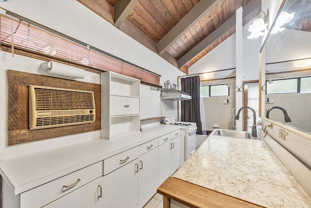 kitchen with sink, gas range gas stove, white cabinetry, lofted ceiling with beams, and wooden ceiling