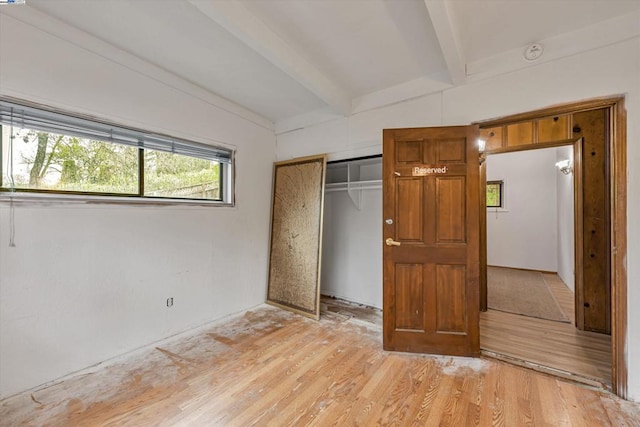 unfurnished bedroom with vaulted ceiling with beams, light hardwood / wood-style floors, and a closet