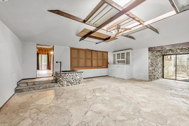 unfurnished living room featuring lofted ceiling with skylight and ceiling fan