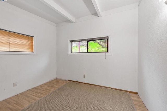 unfurnished room featuring light hardwood / wood-style flooring and beamed ceiling