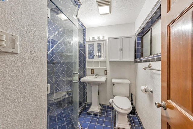 bathroom featuring sink, tile patterned flooring, a textured ceiling, toilet, and walk in shower