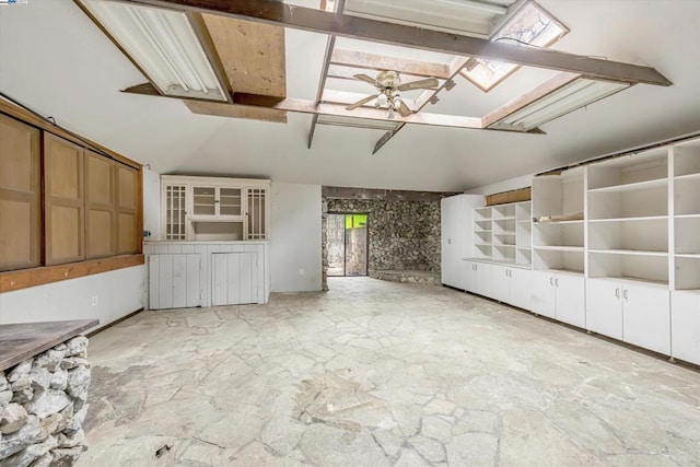 unfurnished living room featuring ceiling fan and lofted ceiling with skylight