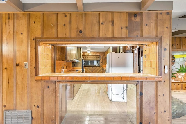 kitchen with white refrigerator and tile countertops