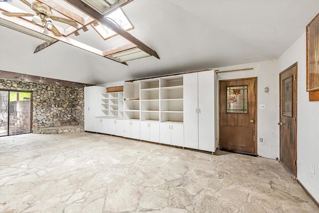 empty room with ceiling fan and vaulted ceiling with skylight