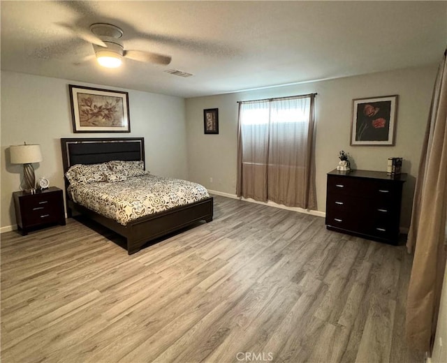 bedroom with ceiling fan, light hardwood / wood-style floors, and a textured ceiling