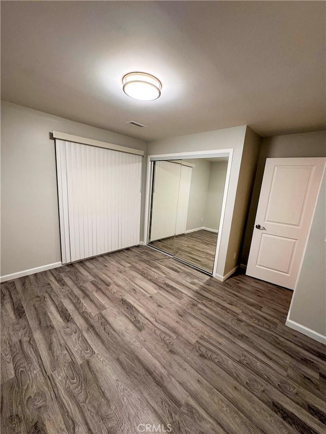 unfurnished bedroom with dark hardwood / wood-style floors and a closet