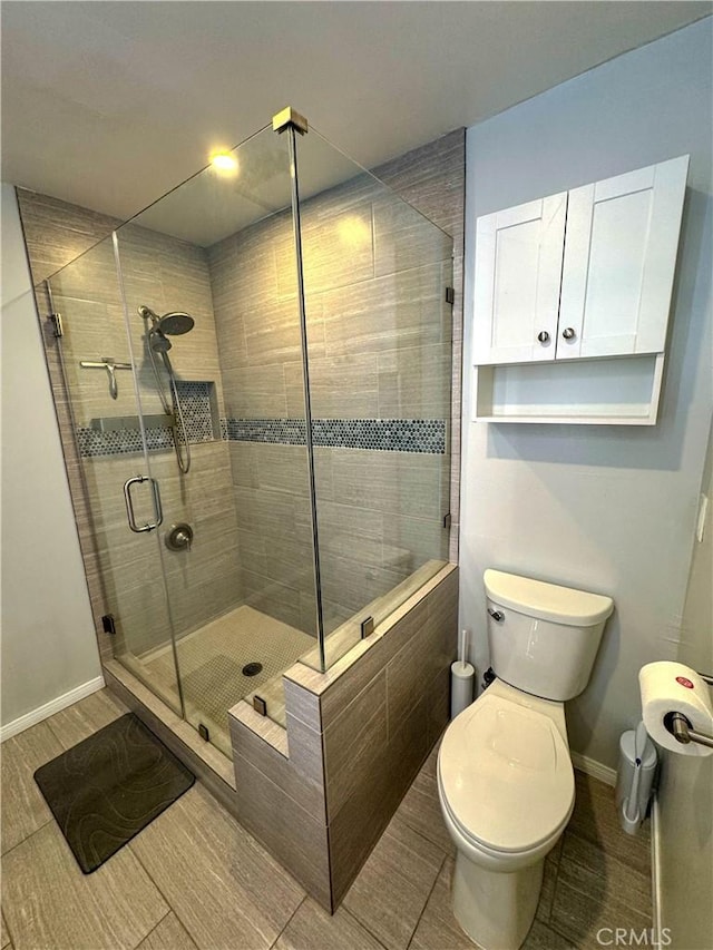 bathroom featuring toilet, a shower with door, and hardwood / wood-style floors