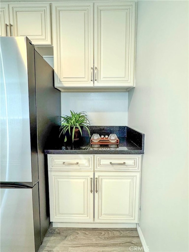 kitchen with dark stone counters, stainless steel fridge, light hardwood / wood-style floors, and cream cabinetry