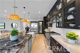 kitchen featuring hanging light fixtures, stainless steel stove, light hardwood / wood-style floors, and dark stone counters