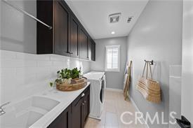 washroom featuring cabinets, light tile patterned flooring, separate washer and dryer, and sink